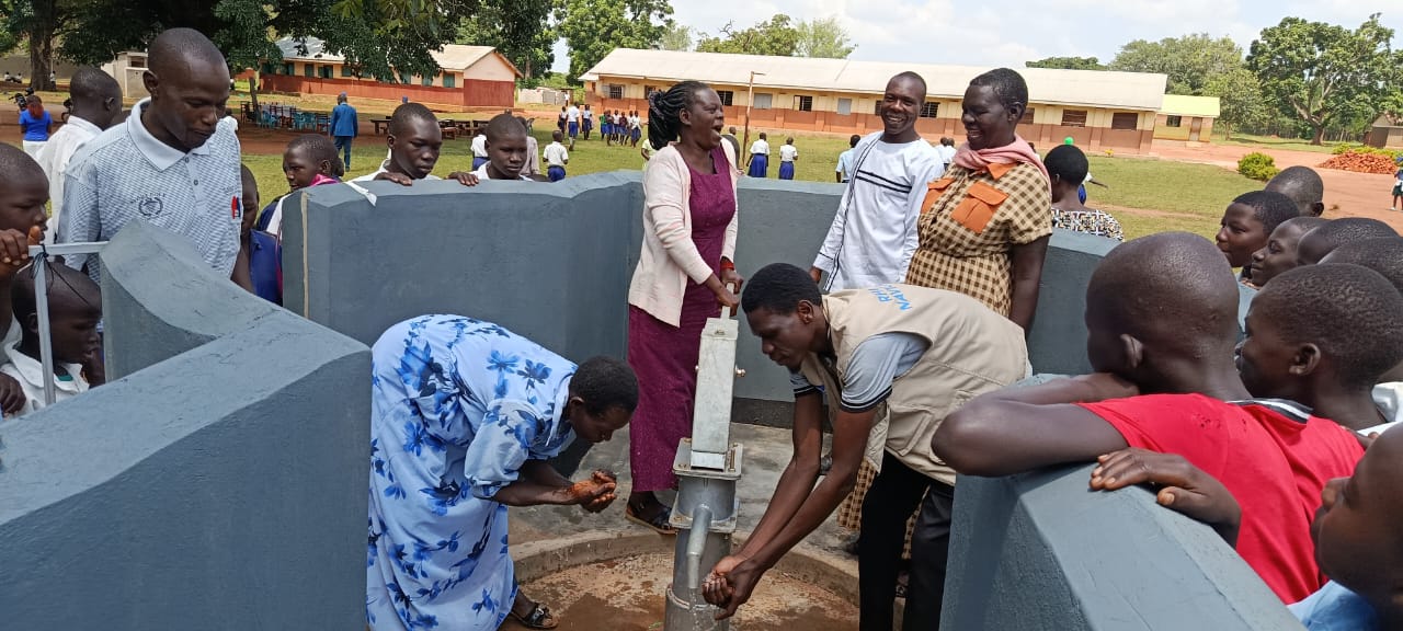 Community members testing water at a hand pump