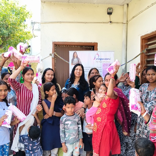 Women and children gathered at a PRAMAN Foundation community outreach activity, with hygiene products held aloft