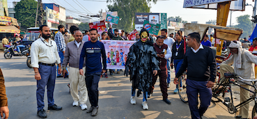 A group walks along a neighbourhood street carrying awareness banners.