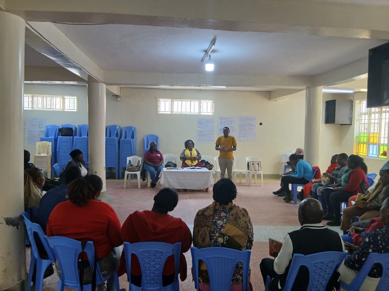 Adults seated in a hall during a parenting training session.